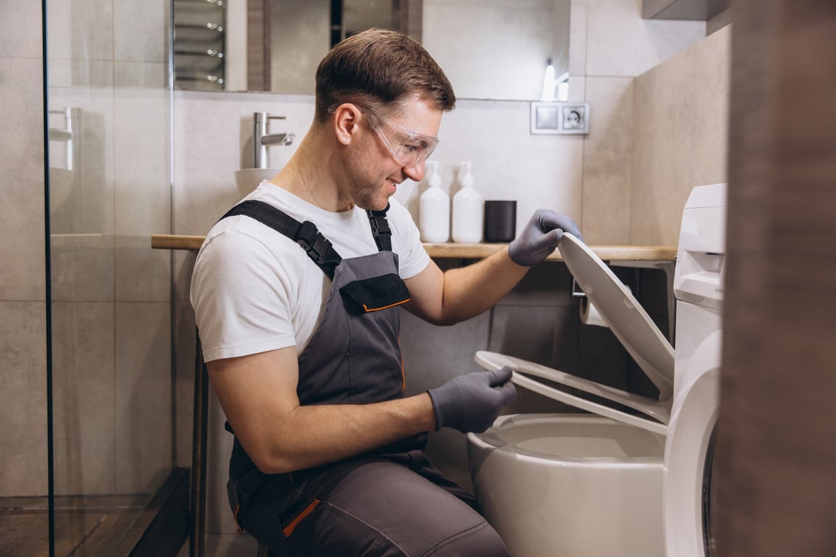 Professionele loodgieter repareert toilet in moderne badkamer